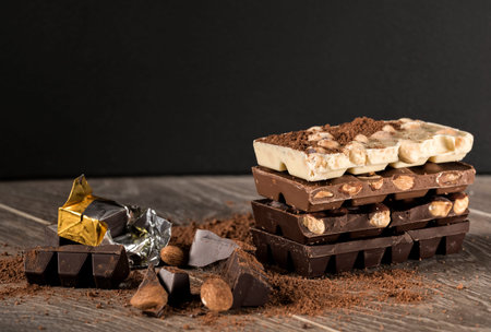 White, milk and dark chocolate with nuts on a wooden table