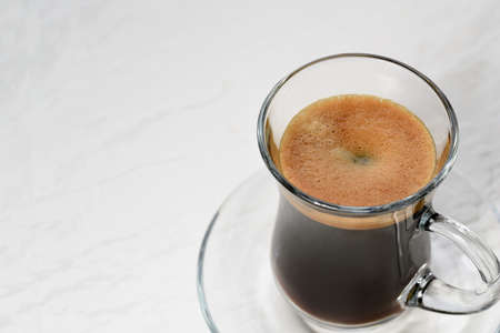 Espresso. Glass espresso cup with coffee beans on a light background.の写真素材