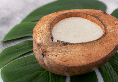 Coconut oil in half coconut on green leave background.の写真素材