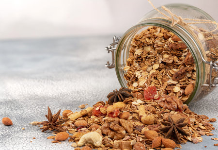 Homemade granola in open glass jar on light background.