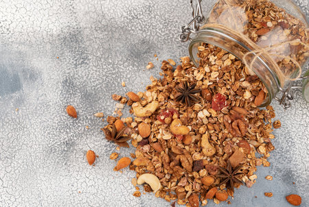 Homemade granola in open glass jar on light background.