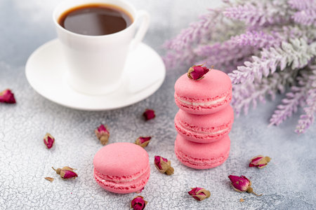 Pink macaroons with dried flower buds and cup of coffee. Pastel colored