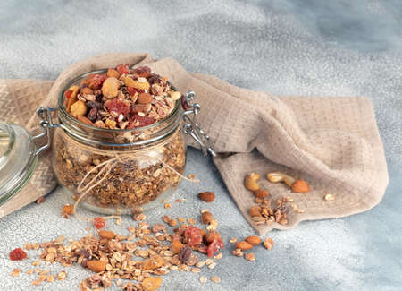 Healthy breakfast - glass jars of oat flakes,granola with dried fruit, berries and nuts on light background .の写真素材