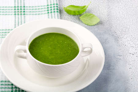 The concept of a healthy, vegetarian or dietary food: cream spinach soup, with pine nuts and basil. With slices of vegetarian carrot bread. On a light background.の写真素材