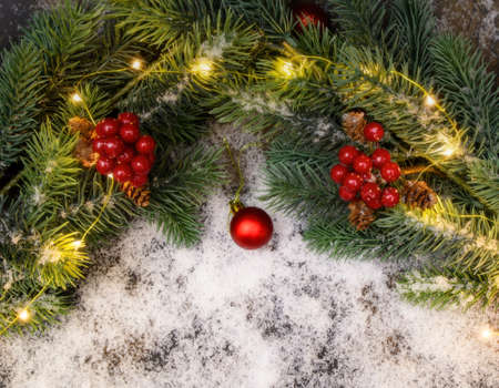 Christmas background with fir twigs, red berries, cones and Xmas lights on snow background with plenty of text space.の写真素材