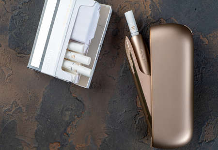 January 15, 2020, Monchegorsk, Russia. Gold iqos electronic cigarette on a dark background, Marlboro and Philippe Morris iqos, which is described as a hybrid cigarette between analog and electronicのeditorial素材