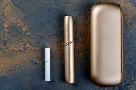 January 19, 2020, Monchegorsk, Russia. Gold iqos electronic cigarette on a dark background, Marlboro and Philippe Morris IQOS, which is described as a hybrid cigarette between analog and electronicのeditorial素材