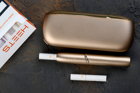 January 19, 2020, Monchegorsk, Russia. Gold iqos electronic cigarette on a dark background, Marlboro...
