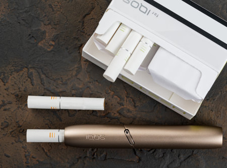 January 19, 2020, Monchegorsk, Russia. Gold iqos electronic cigarette on a dark background, Marlboro...