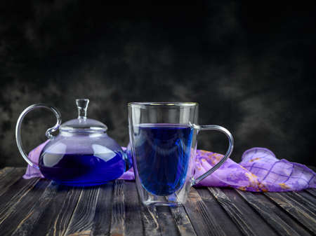 Cup and teapot butterfly pea flower blue tea. Healthy detox herbal drink on dark backgroundの写真素材