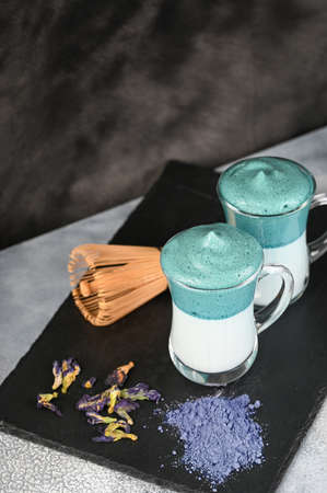 Dalgona Matcha Blue Latte, a creamy whipped matcha in glass on dark background.の写真素材