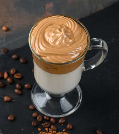 Glass cup with Dalgona frothy coffee trend korean drink latte espresso with coffee foam on black background.の写真素材