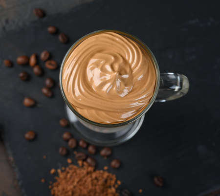 Glass cup with Dalgona frothy coffee trend korean drink latte espresso with coffee foam on black background.の写真素材
