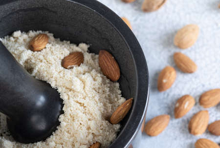 Almond flour in a stone bowl, almonds on old light background. High quality photoの写真素材