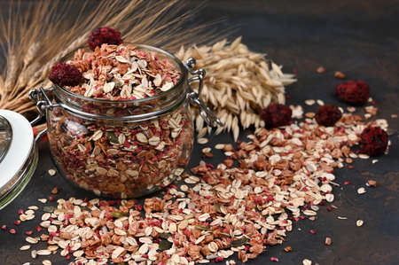 Multigrain organic granola with nuts and dried berries in jar on the black background close up taken with copy space.の写真素材