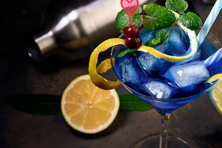 Blue   cocktail with blue curacao liqueur, vodka, lemon juice and soda. Blue cocktail in martini glasses on black background. Copy spaceの写真素材
