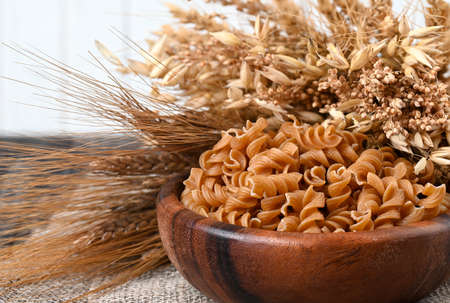 Bowl of wholegrain pasta spirals or fusilli, over light wooden background. Copy spaceの写真素材