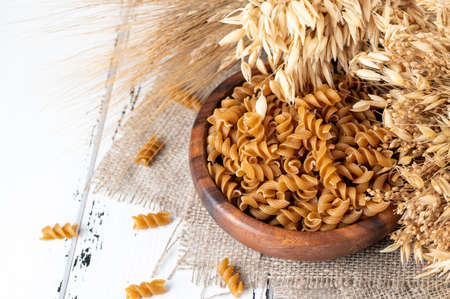 Bowl of wholegrain pasta spirals or fusilli, over light wooden background. Copy spaceの写真素材
