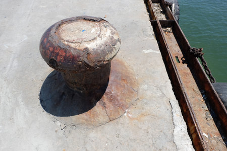 Rusty mooring bollard with ship ropes on seaport