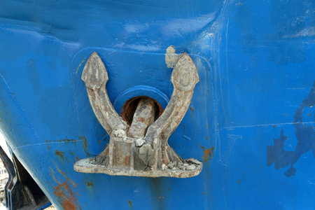 rusting anchor on a blue iron ship