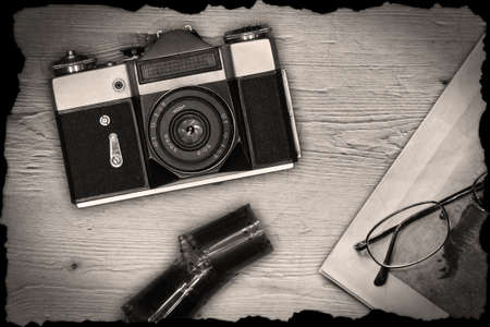 Old manual camera with newspaper, glasses and film on wooden deskの写真素材