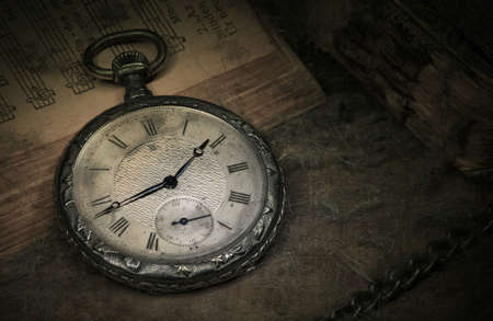 Old pocket watch on books with chain in dirty environmentの写真素材