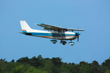 Light general aviation  plane on final over green trees