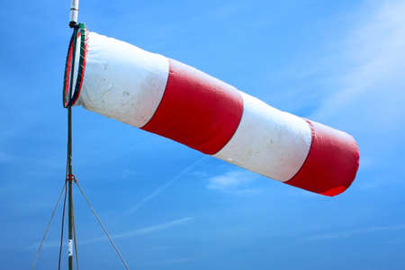 Red and white striped wind sock with blue skyの写真素材