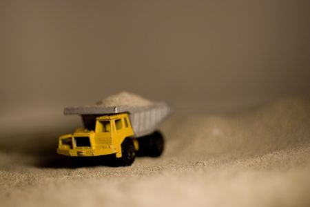 A closeup of a toy dumptruck in sand.の写真素材