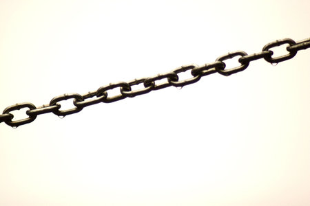 A chain covered in water stung across a white background.の写真素材