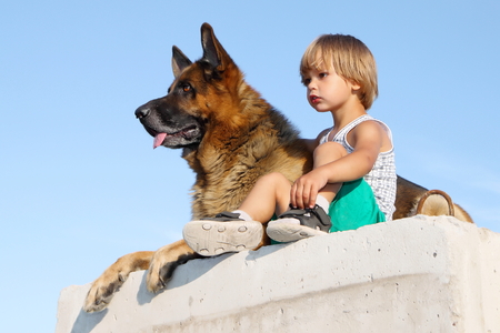 Cute boy and threatening German shepherd looking into distance.の写真素材
