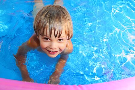 Tanned cheerful boy practicing swimming in the pool.の写真素材