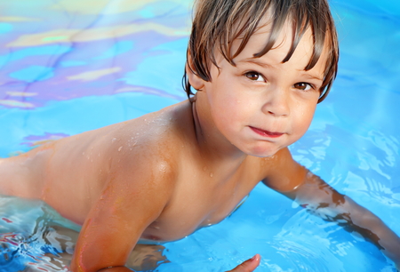 Tanned cheerful boy practicing swimming in the pool.の写真素材