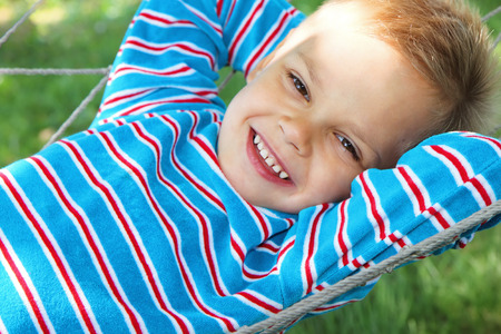 A young boy in a good mood lies in a hammock.の写真素材