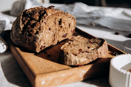 loaf of bread with raisins and cranberries on a wooden board