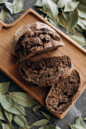 Wholemeal bread with dried cranberries and bay leaves on wooden board