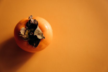 Ripe persimmon on orange background. Minimal concept.の写真素材
