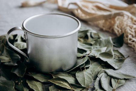 Metal mug with bay leaves on rustic background, closeupの写真素材