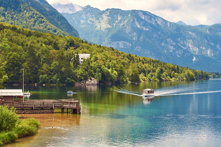 Small ship arrives to the wooden quay at lake Bohinjの写真素材