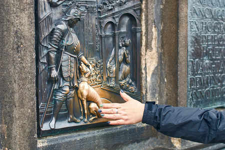 Prague, Czech Republic - September 27, 2014: Tourist is rubbing a bronze plaque of Saint John Nepomuks dog part of the statue of St. John Nepomuk on Charles Bridge for good luck.のeditorial素材