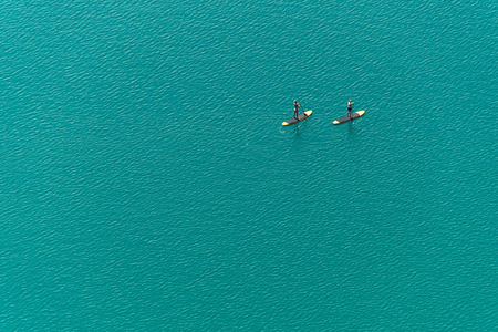 Aerial view of two unidentified stand up paddle boarders on the lakeの写真素材