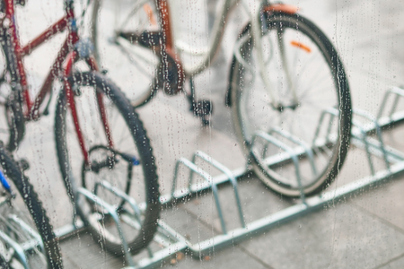 View of parked bicycles through the glass with drops of waterの写真素材