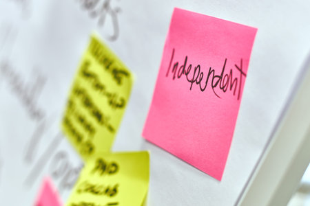 Word independent written on pink and yellow paper stickers attached to a flip chart