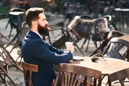 Young stylish businessman is drinking coffee in the morning cafeの写真素材