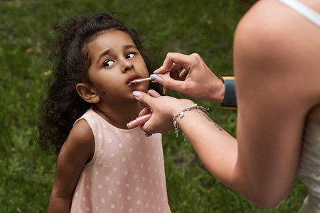 Happy multiethnic family from USA on their European vacation trip. White mother applying hygienic...