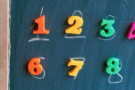 Learning numbers on a blackboard with colorful magnets and handwriting on blackboard during...