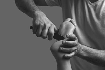 Male masseur hands doing massage on female foot reflex zone in the spa salon using gua sha scraping acupuncture tool.の写真素材