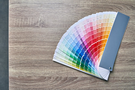 Color wheel palette for choosing paint tone. Various colors on wooden table background with copy space. Interior designer tool.の写真素材