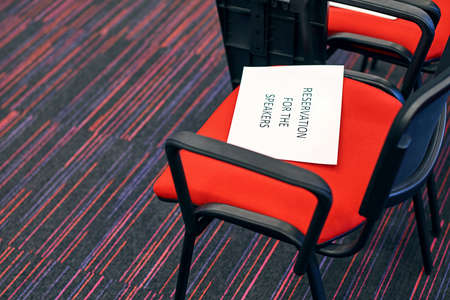 Red and black conference chairs in the auditorium with reservation for the speakers sign on themの写真素材