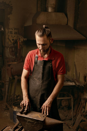 Professional bearded blacksmith in workshop thoughtful portraitの写真素材